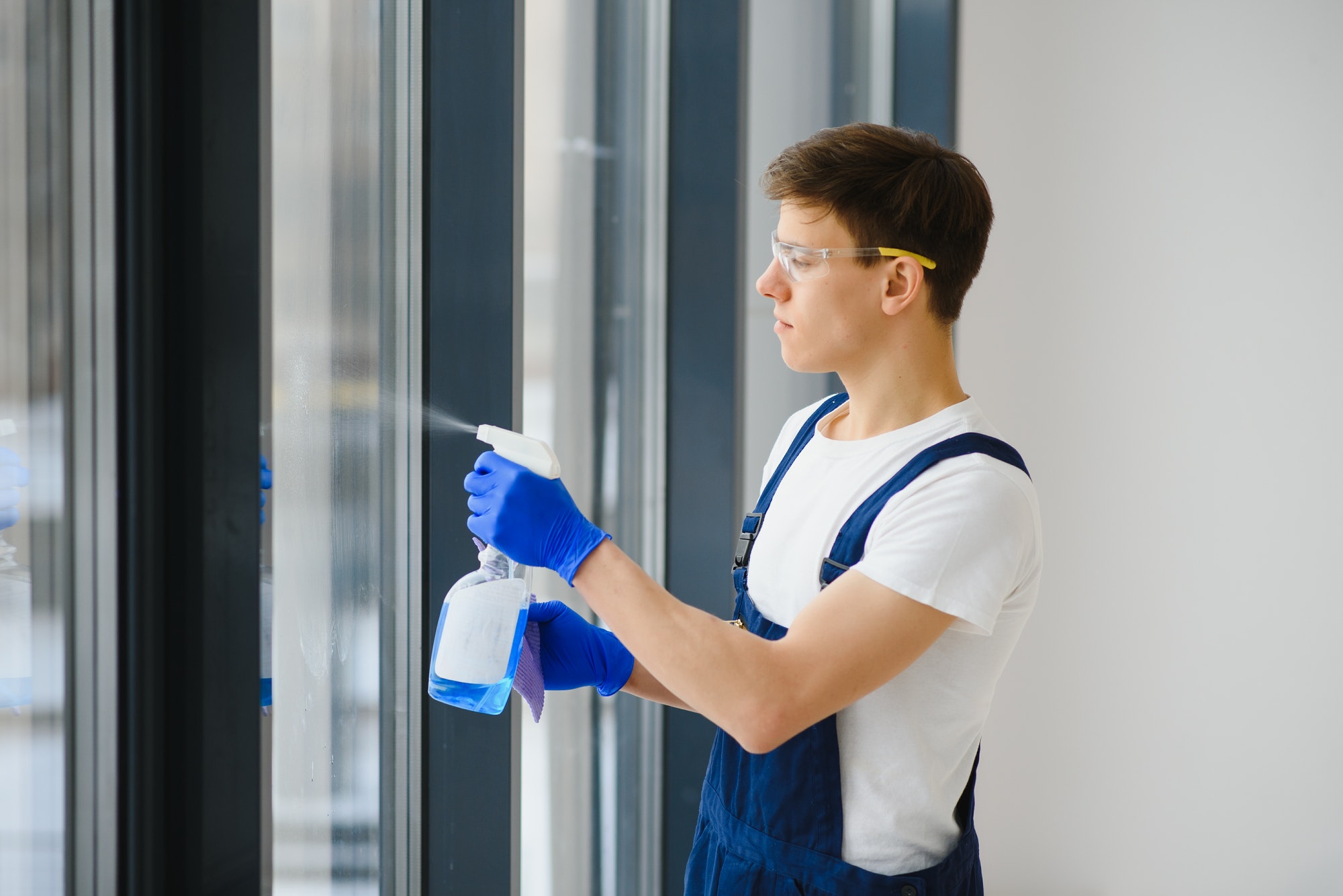 Handyman cleaning the window and smiling in a new house